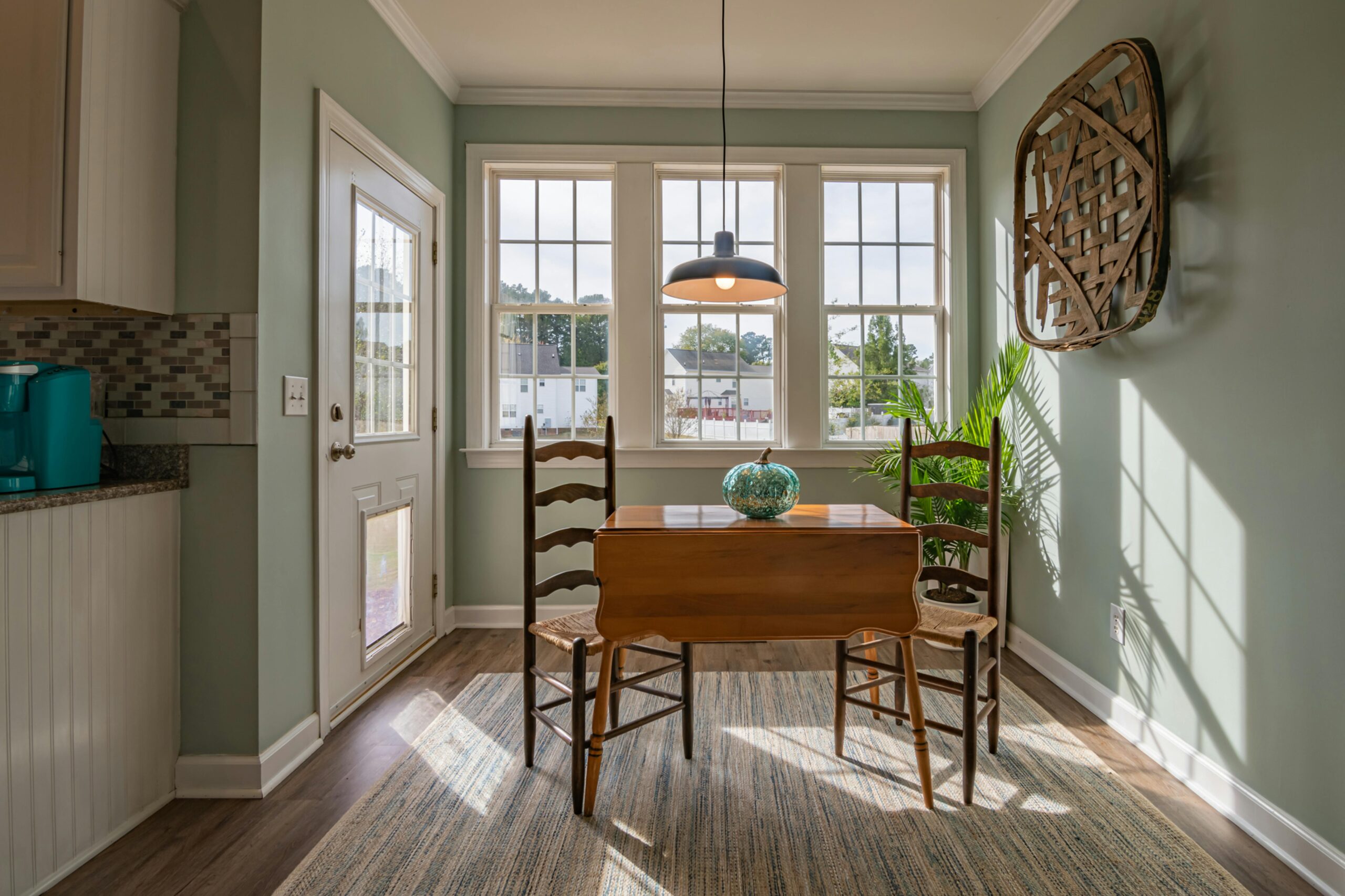 Bright dining area with wooden furniture and large windows showcasing natural light.